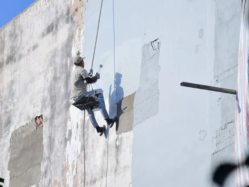 Técnico reparando el revestimiento de una fachada con trabajos verticales en Sevilla